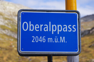 Blue road sign at summit of Oberalppass 2046 meters above sea level on a sunny late summer day. Photo taken September 5th, 2022, Oberalp Pass, Switzerland.