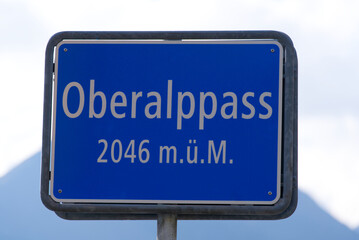 Blue road sign at summit of Oberalppass 2046 meters above sea level on a sunny late summer day. Photo taken September 5th, 2022, Oberalp Pass, Switzerland.