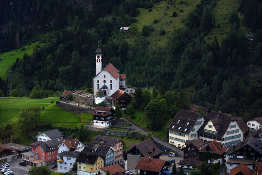 Beautiful scenic view of mountain village Wassen, Canton Uri, with catholic church on a sunny late summer morning. Photo taken September 5th, 2022, Wassen, Switzerland.
