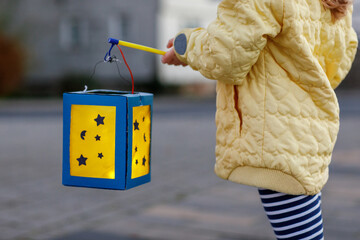 Closeup of little preschool kid girl holding selfmade traditional lanterns with candle for St....