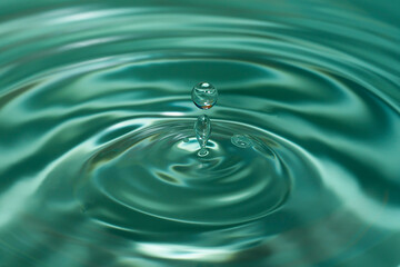 Circles on the water from a fallen drop of water. Blue, aquamarine background. High quality photo