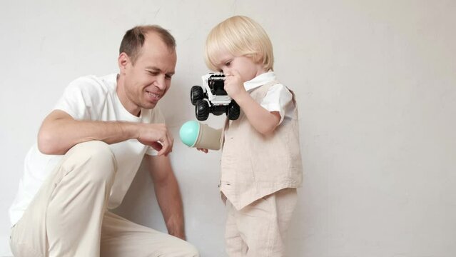 Father plays toys in the children's bedroom with his little son
