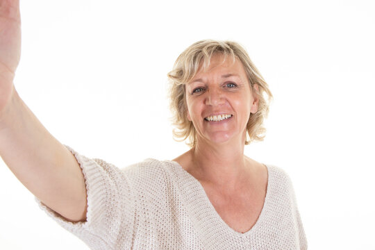 senior elderly woman in sixties year makes cell selfie photo with mobile phone on white background