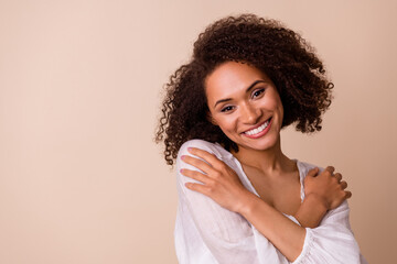Portret van elegante gracieuze persoon handen omarmen schouders brede glimlach geïsoleerd op beige kleur achtergrond