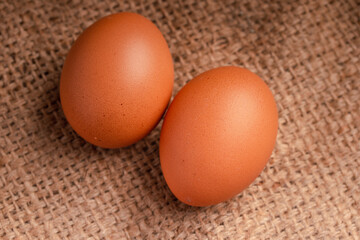 Three fresh chicken eggs on brown background