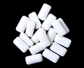 Small rectangular white chewing gums, heap, black background, macro