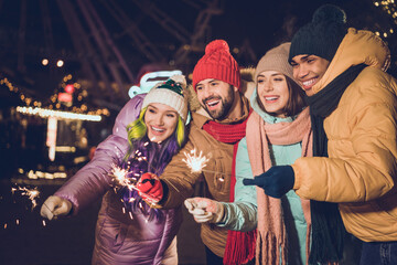 Photo of group carefree cheerful people arms hold bengal lights stick have fun advent evening...