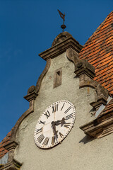 Detail of a building with a big old clock on the roof on a sunny day on a blue sky background, closeup. West Ukraine