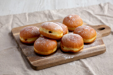 Homemade Apricot Polish Paczki Donut with Powdered Sugar on a Wooden Board, side view.