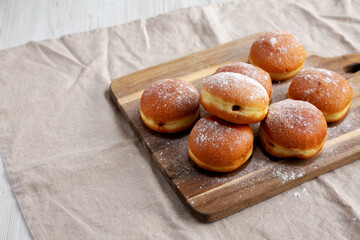 Homemade Apricot Polish Paczki Donut with Powdered Sugar on a Wooden Board, side view. Copy space.