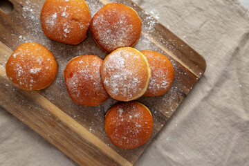 Homemade Apricot Polish Paczki Donut with Powdered Sugar on a Wooden Board, top view. Flat lay, overhead, from above. Space for text.