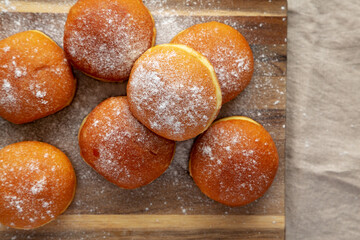 Homemade Apricot Polish Paczki Donut with Powdered Sugar on a Wooden Board, top view. Flat lay,...
