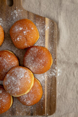 Homemade Apricot Polish Paczki Donut with Powdered Sugar on a Wooden Board, top view. Flat lay,...