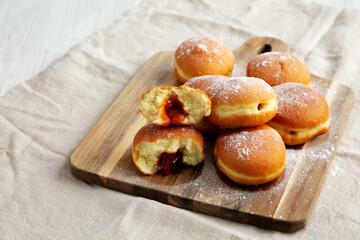 Homemade Apricot Polish Paczki Donut with Powdered Sugar on a Wooden Board, side view.