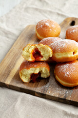 Homemade Apricot Polish Paczki Donut with Powdered Sugar on a Wooden Board, side view. Close-up.