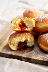 Homemade Apricot Polish Paczki Donut with Powdered Sugar on a Wooden Board, side view. Close-up.