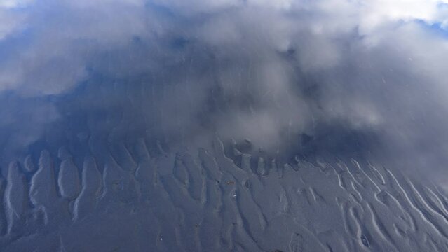 Top down shot of mud waves in black sand of Icelandic beach during cloudy day