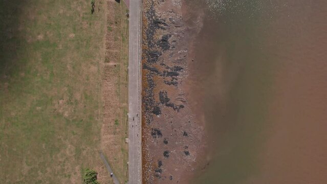 Aerial top down along River Mersey promenade - people walking, cloud shadow