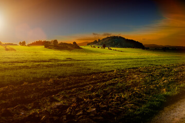 Fototapeta Krajobraz pól rolnych z pagórkami w porze zachodzącego słońca obraz