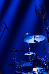 A drums et on stage with microphones pointed at it in blue moody lighting