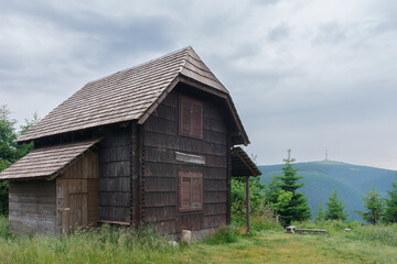 Fototapeta na wymiar Small wooden cottage in Jeseniky mountains, on background television transmitter on mountain Praded