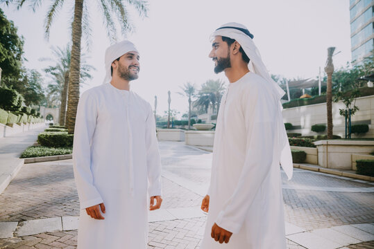 Two young businessmen going out in Dubai. Friends wearing the kandura traditional male outfit walking in Marina