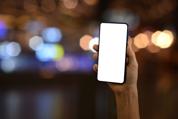 Hand holding smartphone with blank screen on bokeh light background