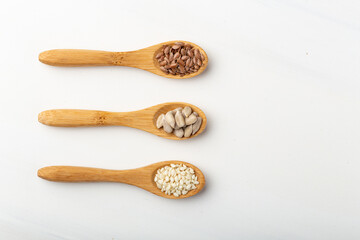 Three spoons with three different seeds, flax seeds, sesame and sunflower seeds