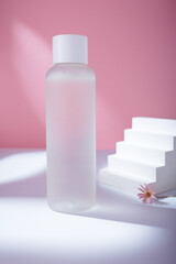 Transparent toner bottle on pink backdrop in harsh light mockup, no brand template. Korean care cosmetics container, copy space