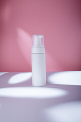 White bottle with dispenser mockup on pink backdrop in harsh light, no brand template. Cleansing moisturizing facial foam container