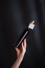 hand holding 250 ml bottle of red wine with mock up label, no brand on black background. Cabernet...