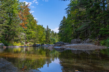 Calm clear glacial water in the bay of the Ammonoosuk riverbed, surrounded by forests in the foothills of Mount Washington in the White Mountain National Forest in New Hampshire.