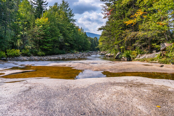 Obraz premium Smooth, glacially chiseled boulders in the Ammonoosuk Riverbed, surrounded by forests near Mount Washington in New Hampshire's White Mountain National Forest.