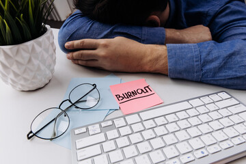 Man in sleeping at the office near laptop and glasses. Burnout concept