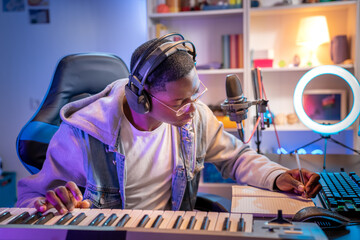 Black man artist recording music while playing electronic piano at home studio.. Creative...