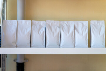 White coffee bean sachets are placed on shelves inside the coffee shop.