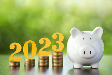 Text of 2023 on top of coins stacks with a piggy bank. 2023 New year saving money and financial...