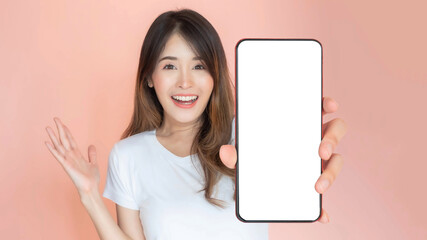 Obraz premium beautiful Asian young woman showing big smart phone with blank screen , white screen empty copy space for advertising banner isolated on pink background , Mock Up Image