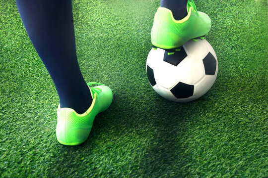 Foots of football player with a ball on green grass football pitch
