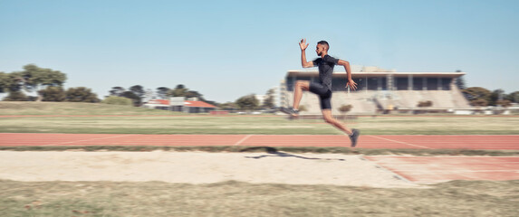 Long jump, athletics and fitness with a sports man jumping into a sand pit during a competition...