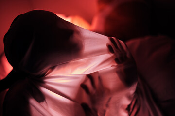 Red lighting, silhouette and hands on sheet for person feeling depressed, trapped and alone....
