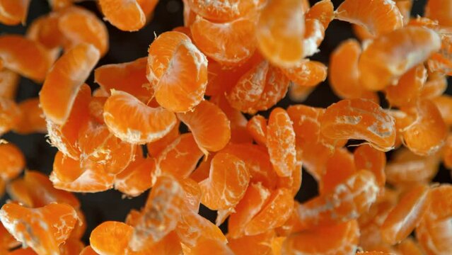 Super Slow Motion Shot of Peeled Tangerines Flying Towards Camera on Black Background at 1000fps.