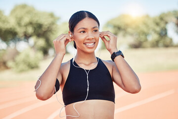 Fitness, exercise and black woman listening to music with earphones for running motivation while outdoor at stadium for marathon or race training. Smile of athlete happy before exercise or run