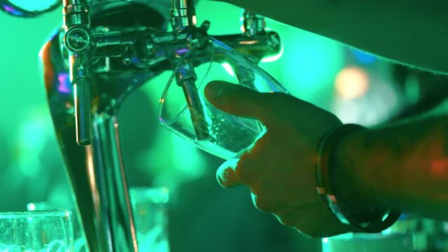 Night party, bartender pours beer into a glass, night club party, multicolored light.