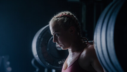 Obraz na płótnie Canvas A Confident Female Powerlifter Training and Working out with Heavy Barbell exercises. A Muscular Inspiring Woman Empowered By her Determination Successfully Lifts Weights. Close Up