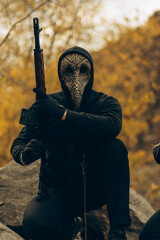 Commando in mask and with machine gun among mountains.