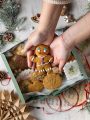 Woman hand holding gingerbread man cookie, Christmas holiday advent on background of festive lights, decorations on rustic table