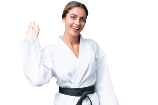 Young Uruguayan woman doing karate over isolated background saluting with hand with happy expression