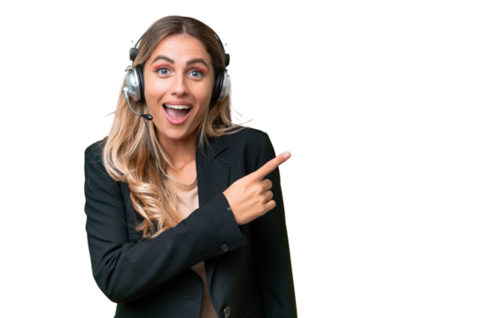 Telemarketer pretty Uruguayan woman working with a headset over isolated background surprised and pointing side