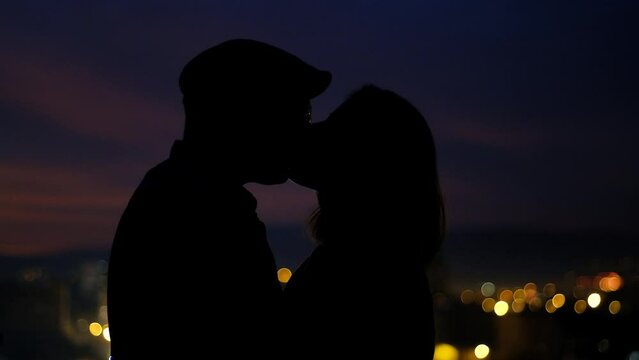 silhouette of a couple kissing in the city at night